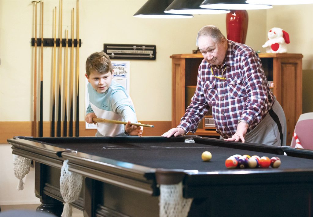 A young visitor and a resident playing billiards together
