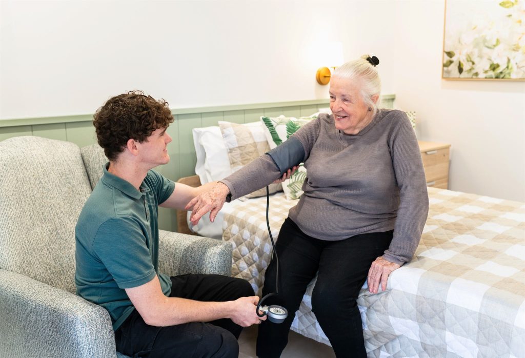 A carer checking a resident's blood pressure in her room